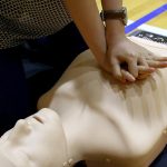Chest compressions on a first aid mannequin