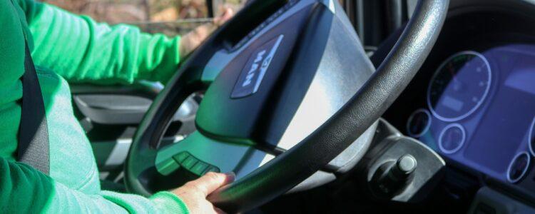 a photo of a person wearing a green sweater in the drivers seat of a van holding a steering wheel